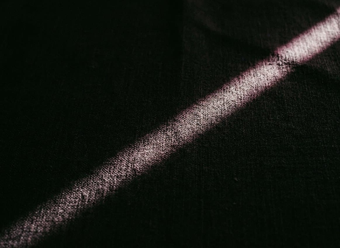 A shaft of light falling across dark gold-woven silk
